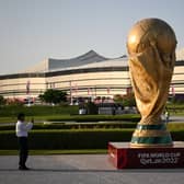 A man takes a picture of a FIFA World Cup trophy replica in front of the Al-Bayt Stadium in al-Khor on November 10, 2022, ahead of the Qatar 2022 FIFA World Cup football tournament. 