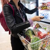 A woman holds a basket of shopping.