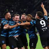 Lee Mack celebrates his goal with World XI teammates including Steven Bartlett (left-centre)