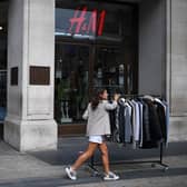 Retail workers move rails of clothes past a H&M store on Oxford Street.