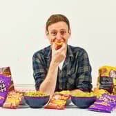 Aldi Chief Crisp Tasting Officer George Critchley with a range of Aldi own brand crisps. (Photo: PR Handout)