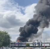 Flames rage through factory as plumes of smoke rise into air.