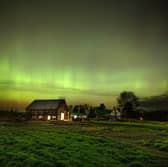 The northern lights fill the sky with green ribbons of electrical charged particles over a barn (Photo by Michael Seamans/Getty Images)