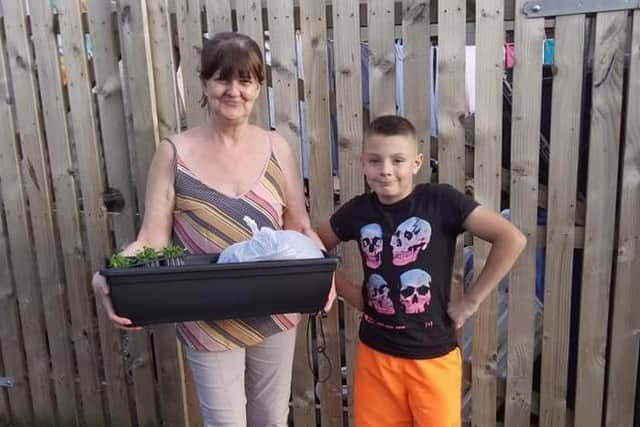 Dunvale resident Geraldine Ringland and her grandson with the window box she received from the Dunclug Youth Forum courtesy of the 
the Little Bit of Paradise Project, funded through the Housing Executive’s
Covid-19 Response Fund
