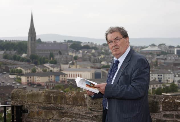 Nobel Peace Prize winner John Hume reads a book titled 'Britian & Ireland Lives Entwined II' before the launch of the book at the Verbal Arts Centre