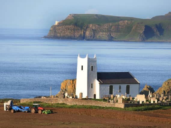 Digging potatoes near Ballintoy Parish Church in August 2011 with Bull Point on Rathlin Island as a backdrop as viewed from the McHenry farm. Picture: Kevin McAuley