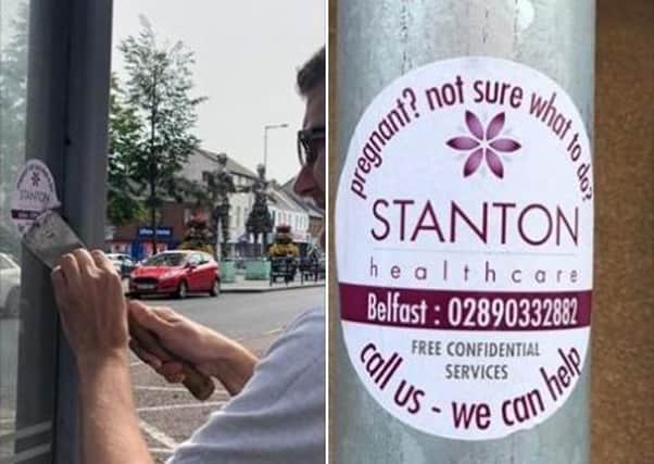 Alliance Councillor Peter Lavery removing an advertising sticker for pro-life counselling organisation, Stanton Health, in Lurgan.