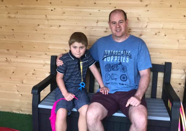 Connor Copelton and his dad Jonathon enjoy a rest after using the playground at the Autism Centre in Carryduff