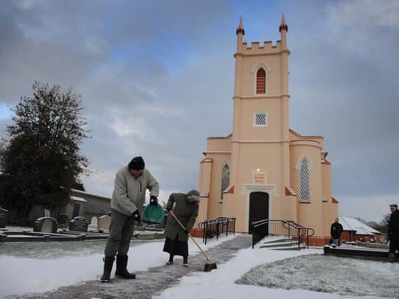 Parishioners clear the pathway for churchgoers after a snowfall at Crumlin Presbyterian in Co Antrim in November 2010. Picture: Colm Lenaghan/Pacemaker