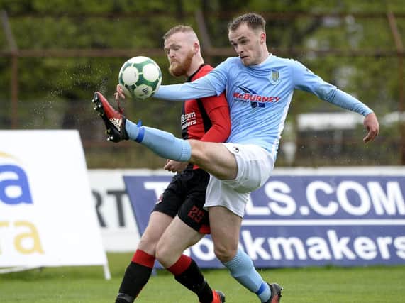 Ballymena United defender Conor Quigley gets his foot in ahead of Crusaders Ross Clarke. Picture by Stephen Hamilton/INPHO