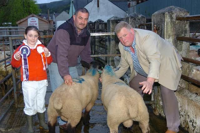 Alana McCullagh displays the winner’s rosettes while Patrick McCullagh, Mountfield, and Drew Heron, judge, display the first prizewinning pair at the show and sale of spring lambs at Gortin Livestock Mart at the end of May 2007