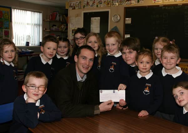 Braidside Primary School P3 pupils Erin Horner and Ben Marks present a cheque for £200 (proceeds of a sponosred non-uniform day at the school) to Frank Diamond of Children In Crossfire. Also included are fellow P3 pupils. BT11-107JC