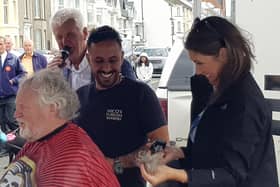 John gets the 'first cut' from media personality Sarah Travers as professional barber Nico looks on with Brian Moore, compere, in the background