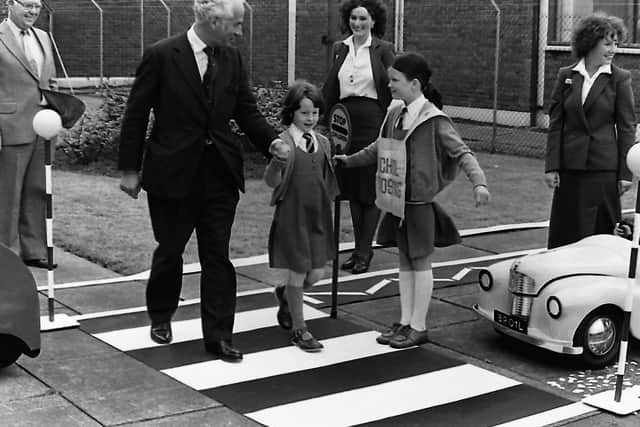 Environment Minister Philip Goodhart is escorted safely across the pedestrian crossing by eight year old Jenny Brown, from Holywood Primary School, in September 1980, after he witnessed a ‘mock’ accident acted by pupils of the school. The minister was at the launching of the BP road safety team’s tour of Northern Ireland when 67 schools would be visited. With the minister are Mr D M Brown, director of BP, Northern Ireland, Angela Gatford and Helen Cuthbert, who would be taking the road safety message to schools across Northern Ireland. Picture: News Letter archives