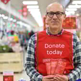 A Tesco volunteer holding a shopping list guide for donations at the launch of the Tesco Food Collection