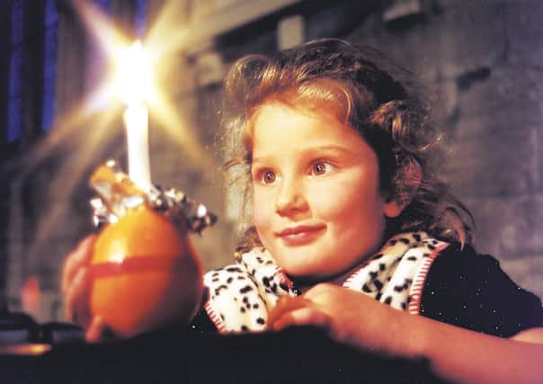 A little girl with a Christingle decoration