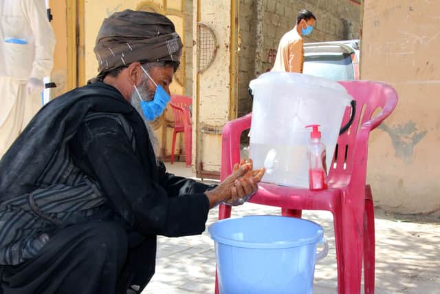 An Afghan man washes his hands before proceeding to a Christian Aid distribution of soap and food, Badghis province.