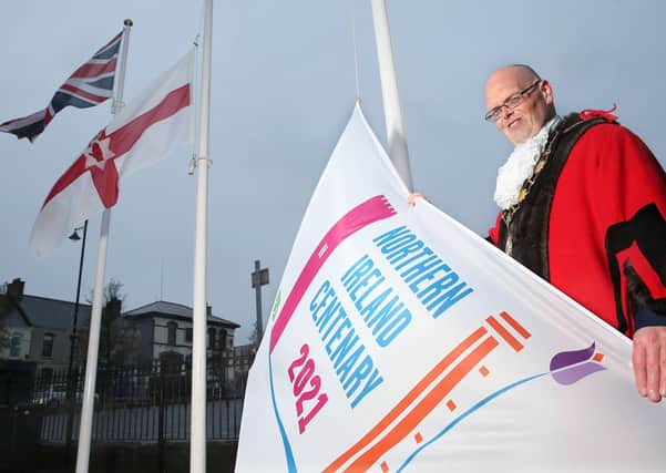 Mayor of Antrim and Newtownabbey, Cllr Jim Montgomery, pictured with the Union Flag, Ulster Banner and the council's Centenary flag.