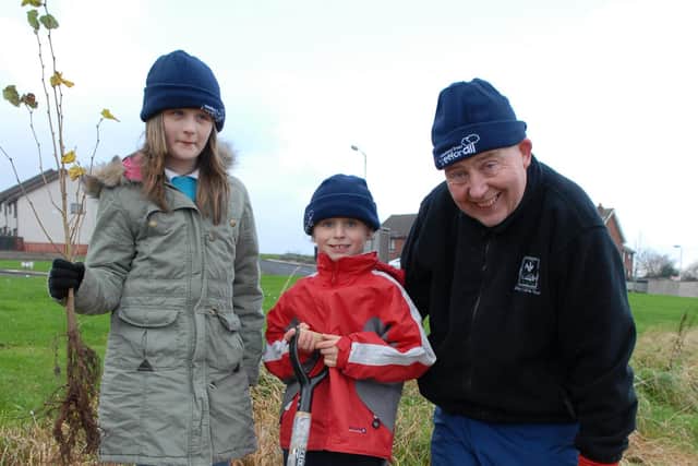 Corran Integrated Primary School pupils Amber and Callum get a hand from Donard McClean of the Ulster Wildlife Trust during the planting at Seaview Wood. LT47-344-PR