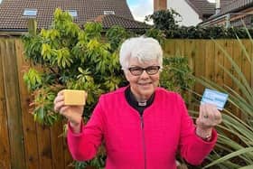 Rev Dr Liz Hughes holds her coronavirus vaccination card and a bar of soap to signify that soap and water remain one of the few defences against infection for people in low-income countries until vaccines are made widely available.