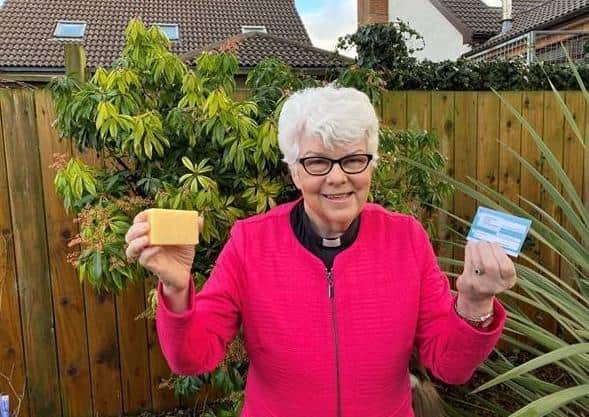 Rev Dr Liz Hughes holds her coronavirus vaccination card and a bar of soap to signify that soap and water remain one of the few defences against infection for people in low-income countries until vaccines are made widely available.