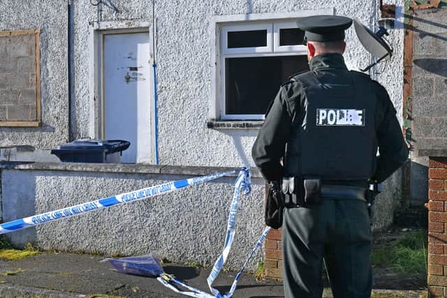 A police officer repositions flowers that were left by sympathisers at the scene of what the PSNI have described as a 'suspicious death'at a house at Carrickdale Gardens off the Tandragee Road in Portadown, County Armagh. Photo Alan Lewis.