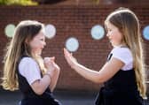 P3 children Scarlett Greggan (left) and Madison Lowry playing patty cake during their lunch break in the playground of Springfield Primary School in Belfast