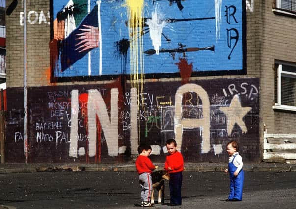 Young children play beside a mural honouring the INLA