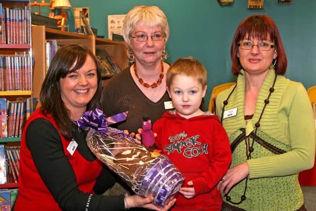 Young Ciaran Martin, winner of the Ballymena Library Easter Egg competition, receives his prize from Maria Higgins (Branch Library Manager), Roberta McAuley and Angela McCrystal. BT14-218AC