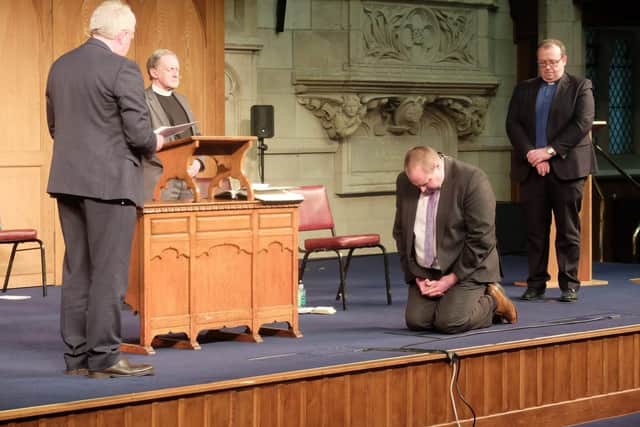 Rev Campbell Mulvenny kneels as he is installed by members of the Route Presbytery Commission (left to right) Rev Alan Buick, Moderator of Route Presbytery, Rev Noel McClean, Clerk of Presbytery and Rev Rodney Moody