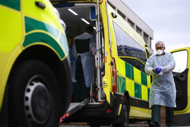 A paramedic wearing personal protective equipment (PPE) exits an ambulance