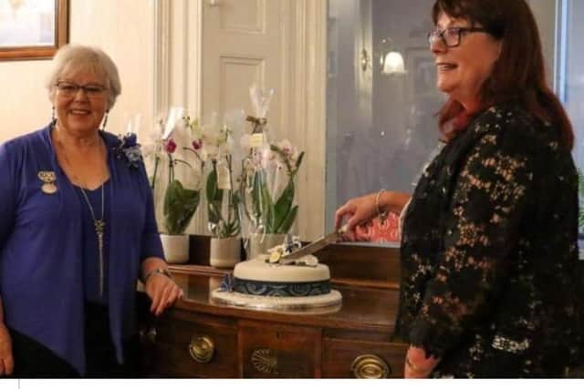 Marretta Coleman, chair of NIGFAS, joins Alison McAuley, chair of the Greenisland club,  as she cuts the celebratory cake.