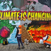 Artists paint a mural on a a wall next to where the COP26 UN Climate Summit will take place in November.