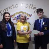 Loreto College Senior Prefects Jessie McGilligan and Khlad Al-Hasan present a cheque for £625 to Barbara Dempsey of Marie Curie