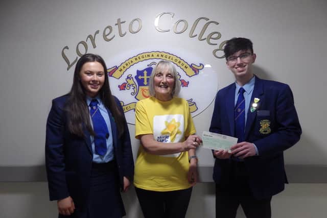 Loreto College Senior Prefects Jessie McGilligan and Khlad Al-Hasan present a cheque for £625 to Barbara Dempsey of Marie Curie