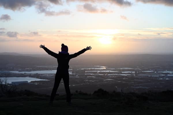 Celebrating the arrival of 2022 from the top of Cave Hill as the sun rises over Belfast on New Year's morning. Picture: Michael Cooper