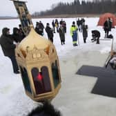 A Russian Orthodox priest conducts a service in the icy water on Epiphany at a hole in the form of Orthodox Cross at a lake in Orlino village, 70 kilometers (43 miles) south of St Petersburg, Russia in January 2018. Thousands of Russian Orthodox Church followers plunged into icy rivers and ponds across the country to mark Epiphany, cleansing themselves with water deemed holy for the day. (AP Photo/Dmitri Lovetsky)