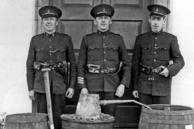 Constable James McBryde [far right] with RUC colleagues Constable Patrick Donnelly, Sergeant John Glenanne in 1935. The officers are pictured with confiscated poteen from Rosslea in Co Fermanagh. Picture: News Letter archives
