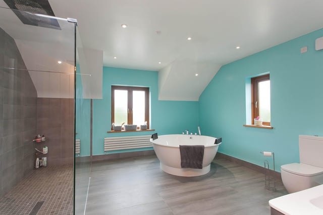 The main bathroom with luxurious circular bath, double basins in vanity units, walk in double shower / wet room.