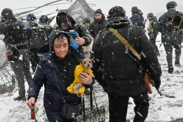 TOPSHOT - A woman carries her dog during the evacuation by civilians of the city of Irpin, northwest of Kyiv, on March 8, 2022. - More than two million people have fled Ukraine since Russia launched its full-scale invasion less than two weeks ago, the United Nations said on March 8, 2022. (Photo by Sergei SUPINSKY / AFP) (Photo by SERGEI SUPINSKY/AFP via Getty Images)