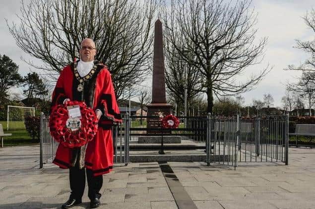 Cllr Jim Montgomery replacing a wreath after a vandalism attack at Glengormley War Memorial last year.