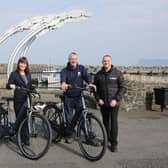 Infrastructure Minister Nichola Mallon delivers the first of 20 E-bikes to Michael Cecil, Chair of the Rathlin Development and Community Association. Also pictured is Philip McCallen who is supplying the E-bikes which will be made available for use by locals and those working on the island
