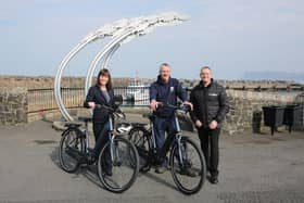 Infrastructure Minister Nichola Mallon delivers the first of 20 E-bikes to Michael Cecil, Chair of the Rathlin Development and Community Association. Also pictured is Philip McCallen who is supplying the E-bikes which will be made available for use by locals and those working on the island