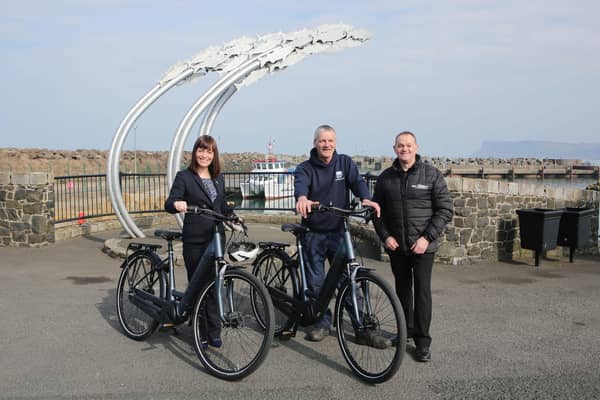 Infrastructure Minister Nichola Mallon delivers the first of 20 E-bikes to Michael Cecil, Chair of the Rathlin Development and Community Association. Also pictured is Philip McCallen who is supplying the E-bikes which will be made available for use by locals and those working on the island