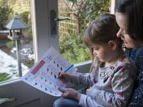 RSPB Big Garden Birdwatch. Mother and her daughter counting birds in their garden, Bedford, UK, January 2013