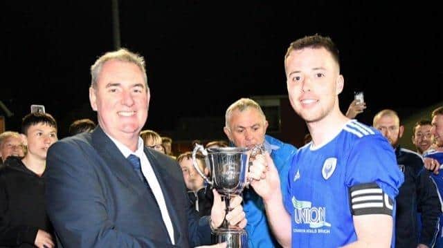 Captain of Craigavon City FC John Cochrane receiving the Alan Wilson Cup from Mid Ulster League Chairman Sean O’Neill. Photo courtesy of Eamon Shanks.