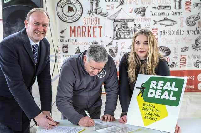 Eoin McConnell from Naturally North and Glens CIC signs the Real Deal Charter alongside Damien Doherty, Chief Inspector of the Trading Standards Service and Shauna McFall, Market Manager