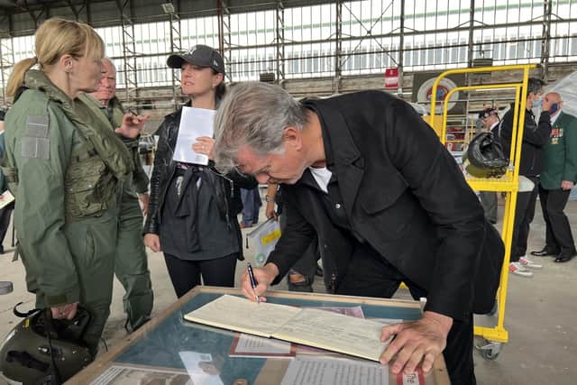 Piuerce Brosnan signs the visitors vook at the Ulster Aviation Society during his recent visit.  Photo by  E. England for Ulster Aviation Society
