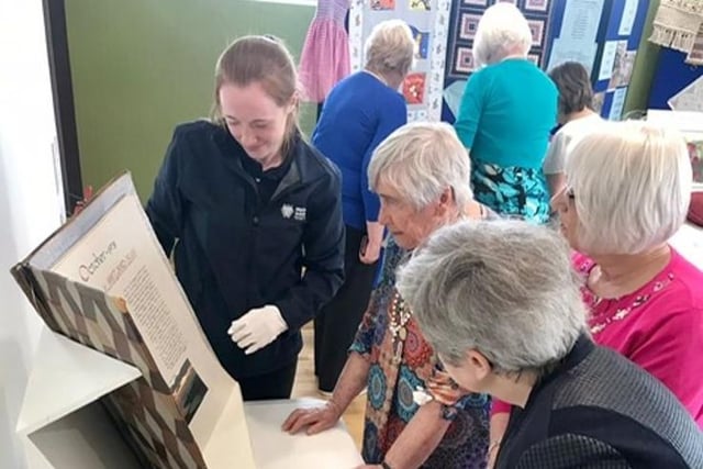 Karen, from Mid and East Antrim Council shows members the historical scrap books which are currently stored at the Carnegie Museum.