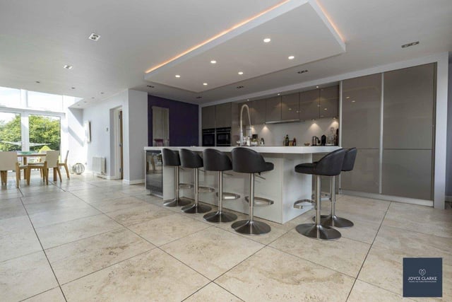 The bespoke modern kitchen has an island with seating and is open plan to the dining area.